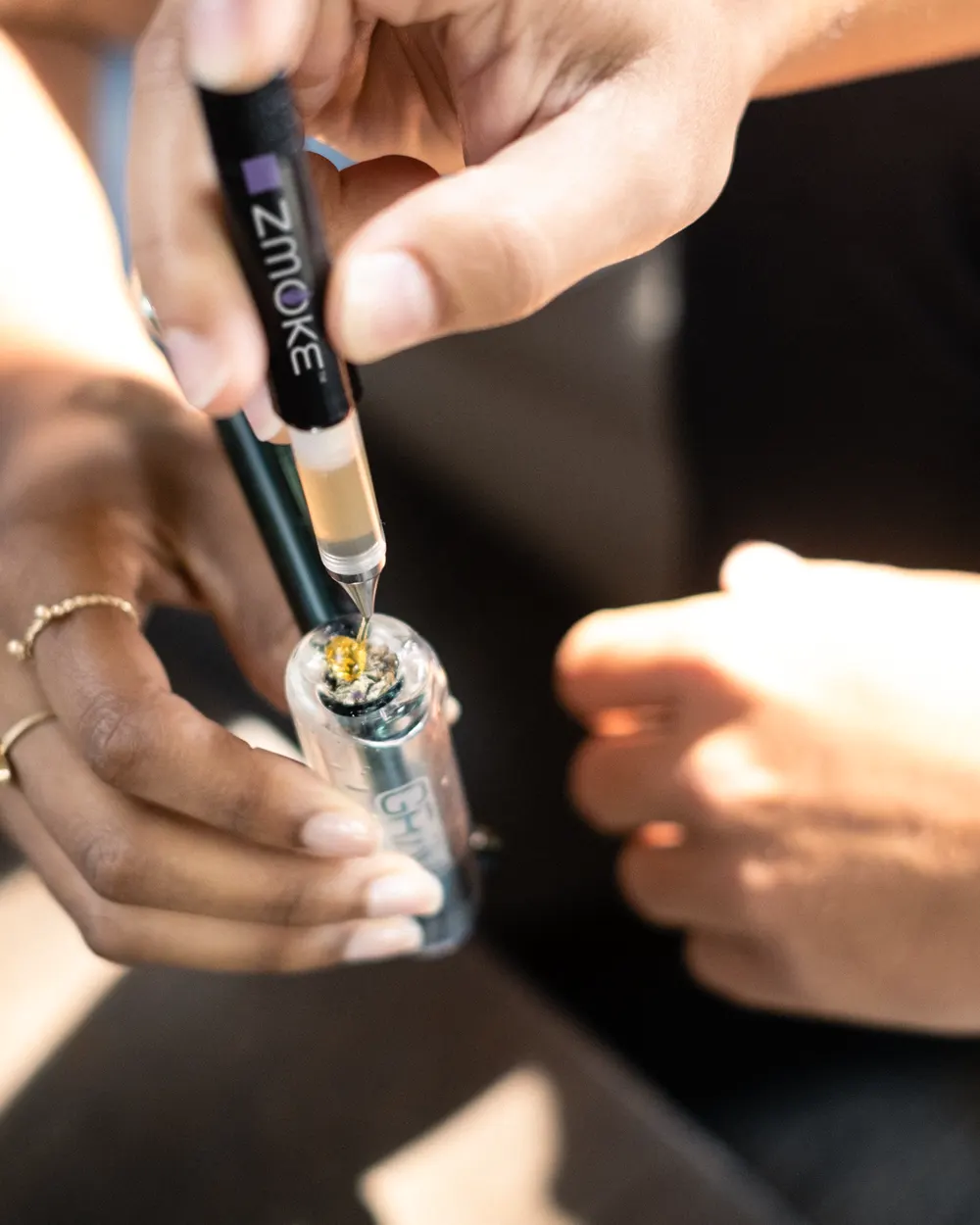 A ZMOKE applicator placing concentrate into a glass bowl