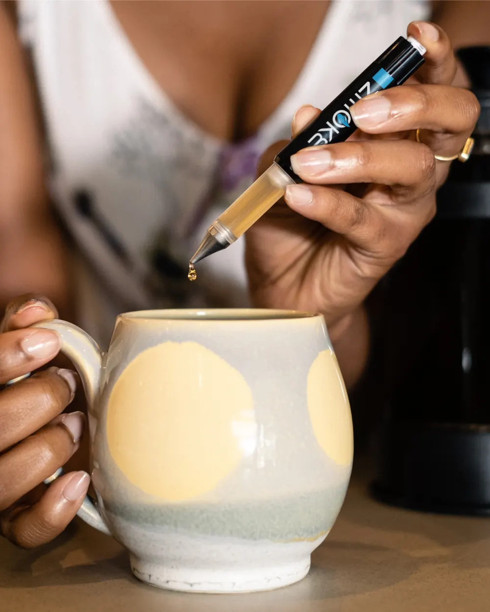A ZMOKE applicator releasing a drop into a mug