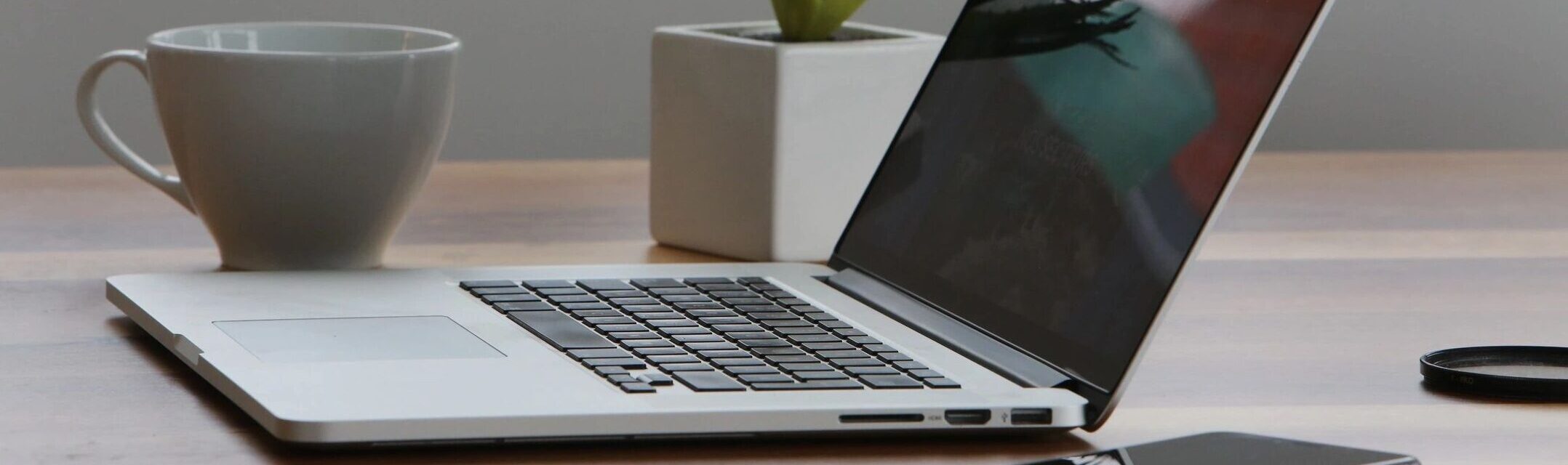 Sideview of open laptop computer on desk with phone